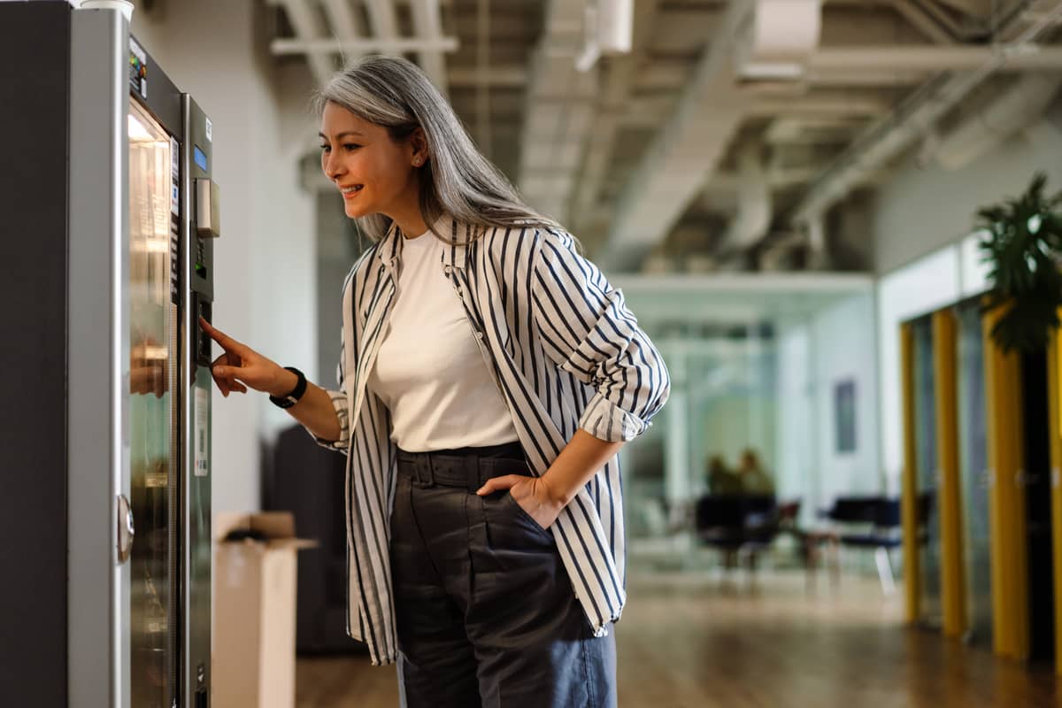 Woman using a vending machine in a bright open-plan office