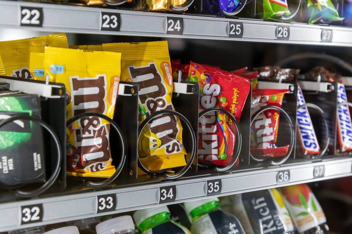 Close-up of snacks and candy held on numbered vending machine coils