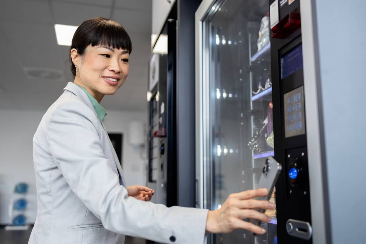 Woman in a white blazer paying at the touchscreen of a vending machine